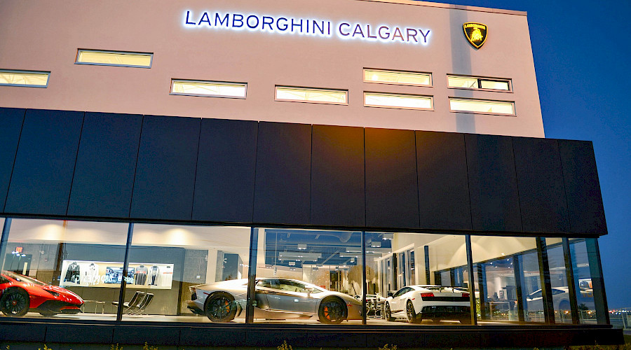 The exterior of the Lamborghini Calgary building in the evening, with windows that display cars inside.