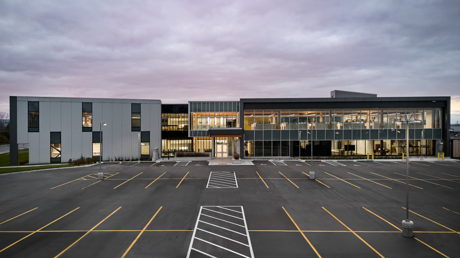Image of Chandos Construction project at dusk in Ottawa, Ontario. The floor to ceiling windows feature showcase the mass timber interior elements.