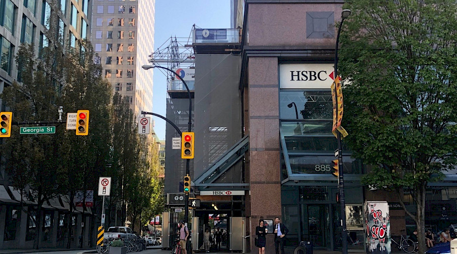 A crosswalk on a large street in front of the HSBC building.