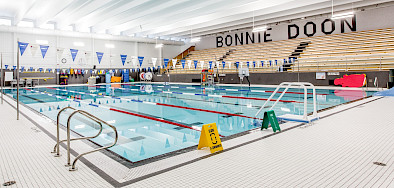 Lanes in a bright blue pool with bleachers in the background and "Bonnie Doon" painted in large black letters on the wall.