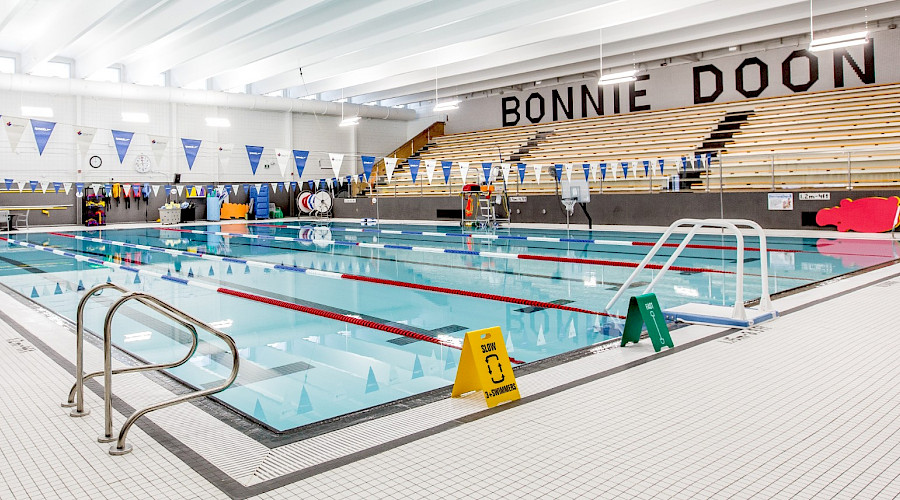 Lanes in a bright blue pool with bleachers in the background and 