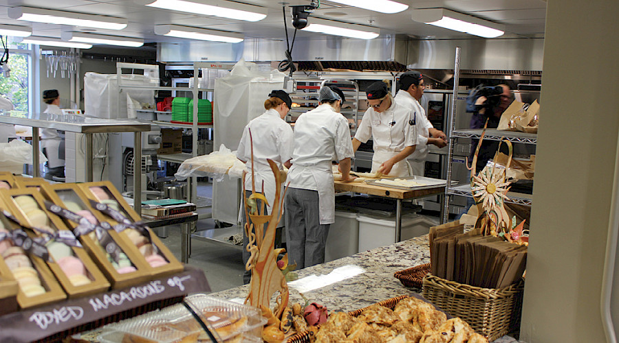 A photo of student chefs working together in a kitchen, with their bakery items on display.