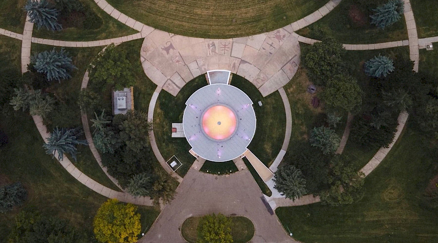 An aerial shot of the Queen Elizabeth II Planetarium surrounded by green grass and trees.
