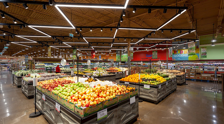 Rows of fresh produce on top of wooden cases in a large supermarket.
