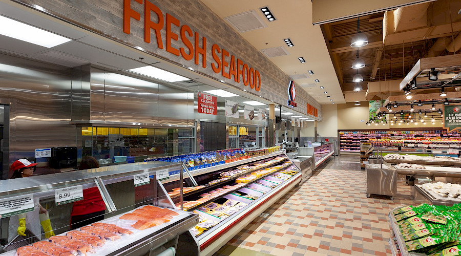 Fresh fish on ice and shelves of other food products underneath a sign that reads 