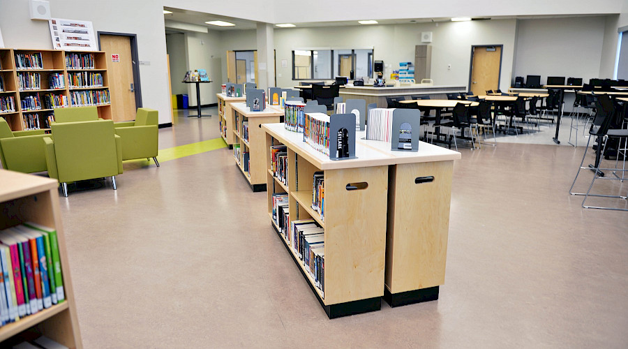 A library filled with round tables and multiple shelves of books.