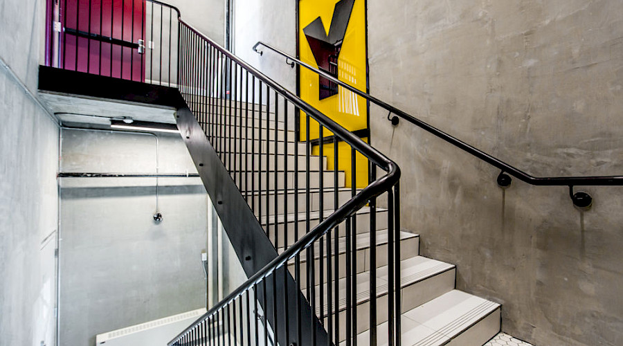 A bright yellow sign with a large black Y on it on the walls of a staircase going up.