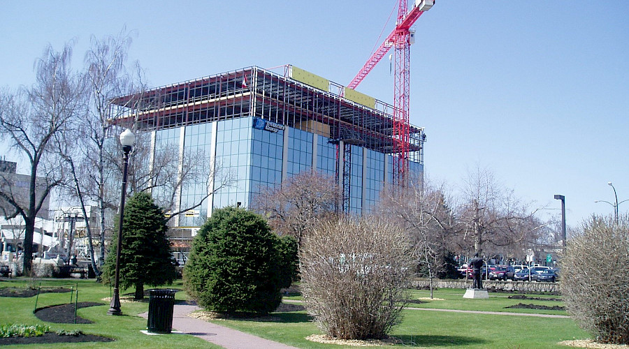 A large glass building under construction in the middle of a park.