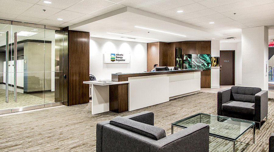 A waiting area in front of a large white and wooden reception desk.