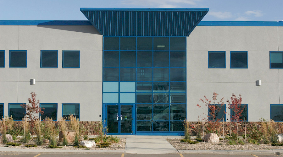 Two doors surrounded by large glass windows at the front entrance of the Peak Energy Services building.