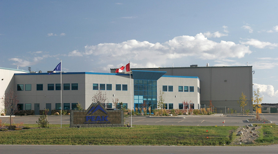 Canadian and Albertan flags waving beside a sign that says 