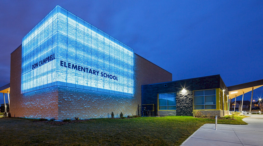 A photo of the lit up Don Campbell elementary school at night.
