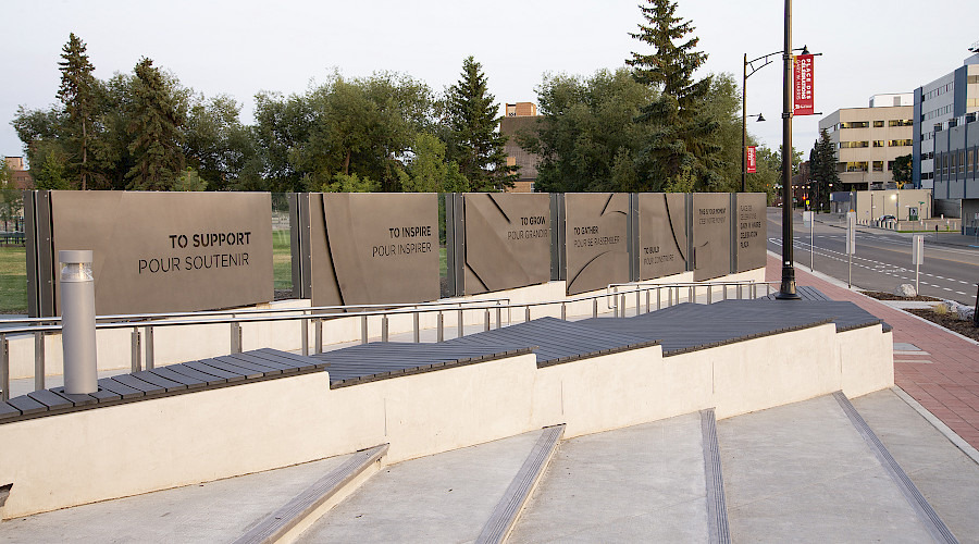 Signage in front of the Gary W Harris Celebration Plaza with trees in the background.