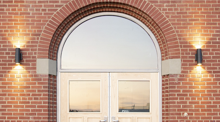 A lit up round doorway on a red brick building.