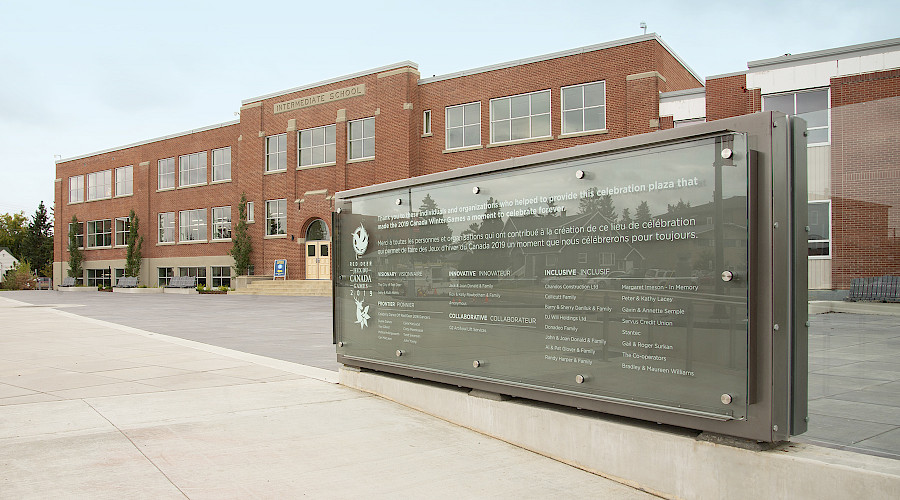 A sign before a large red brick school.