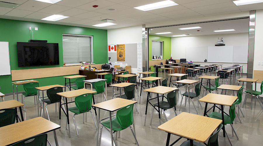 A green classroom with rows of desks and chairs.