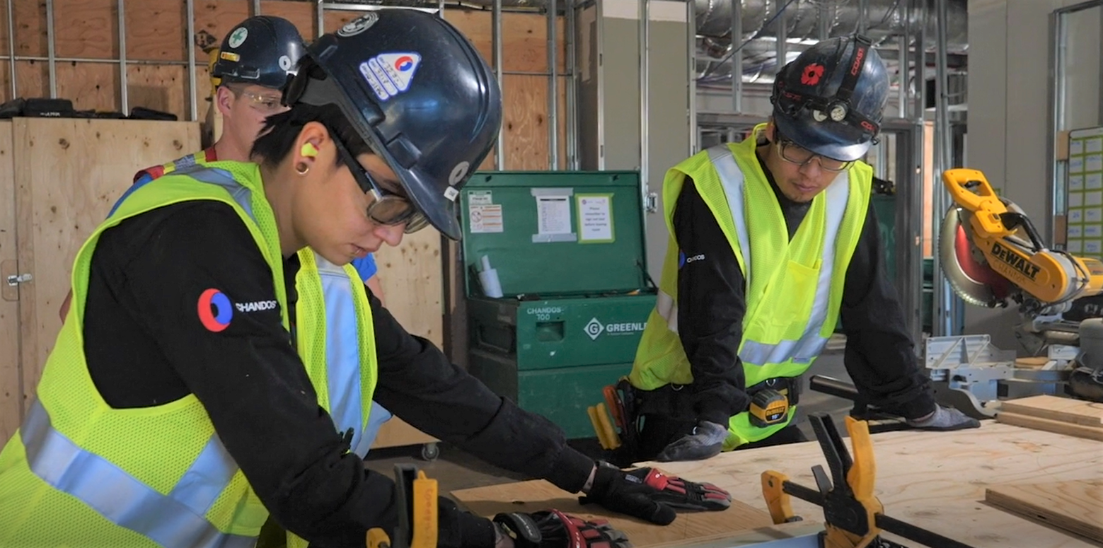 Three Chandos construction carpenters in safety gear working together on site.