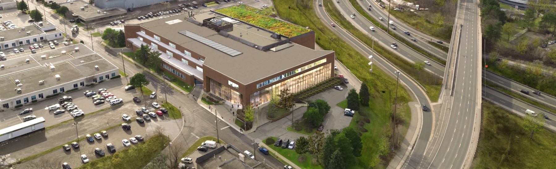 A rendering of an aerial shot of the McMaster Innovation Park, with cars and people in the parking lot on the left side of the building and a large highway on the right side.