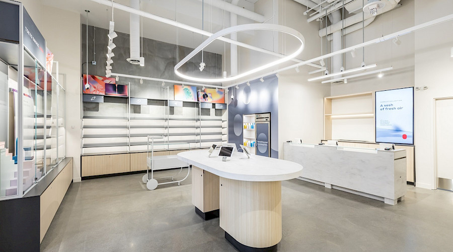 A small island in a bright room with empty shelves and modern light fixtures.