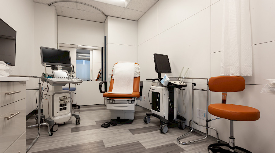 A medical chair lined with paper in a bright white doctor's office.