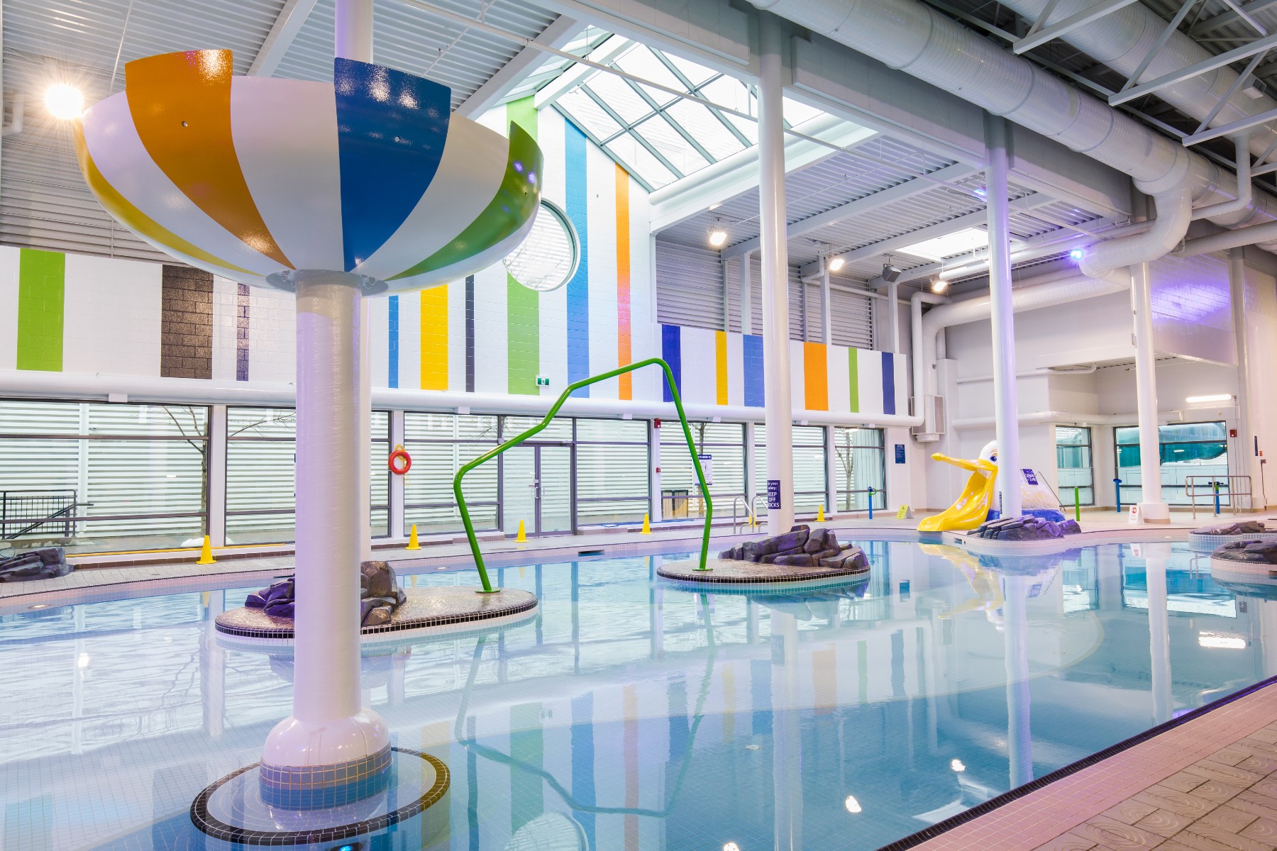 A lazy river in a pool with colourful decorations and walls.