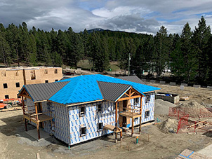 An aerial shot of a housing building under construction with large green trees in the background.