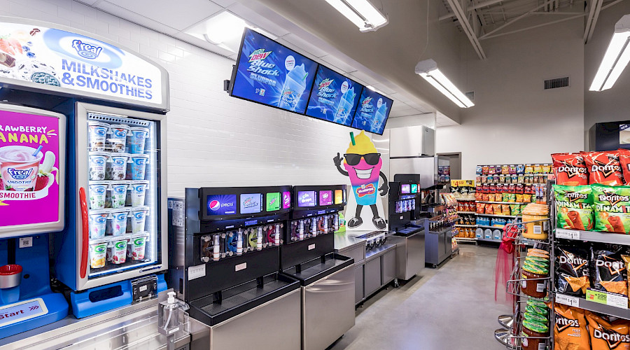 Slurpee machines against a wall across rows of chips and other snacks.