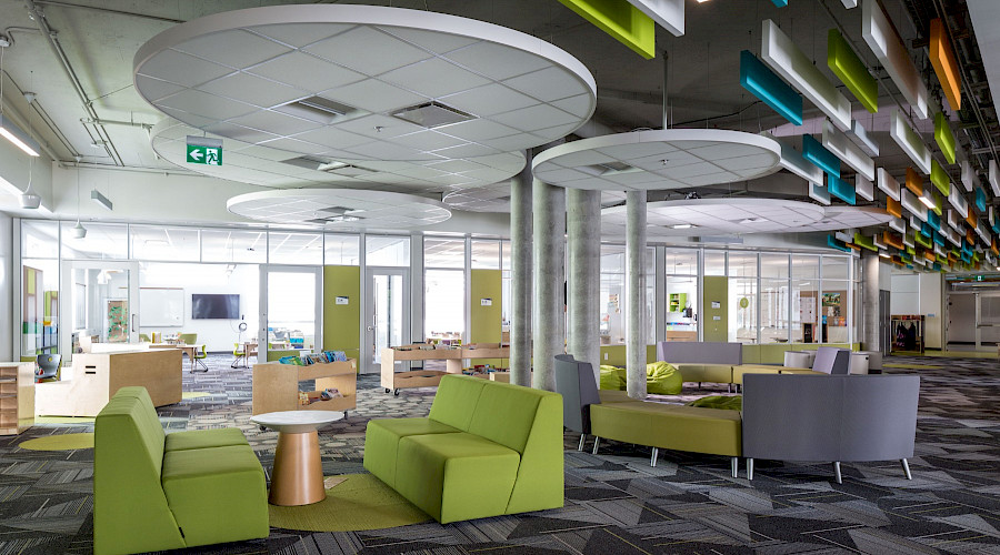 Green and grey sofas with tables in a bright and fun common room.