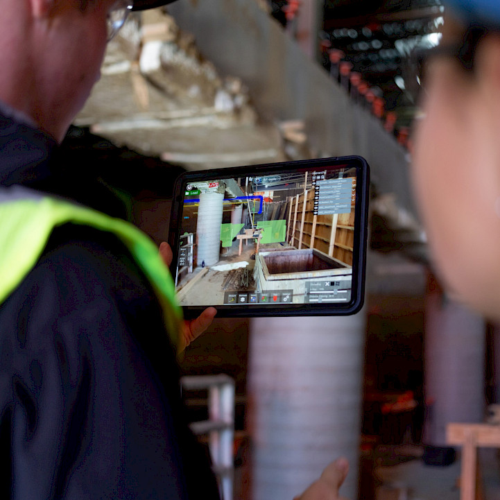 Two construction workers using Virtual Design Construction and BIM technology on site.