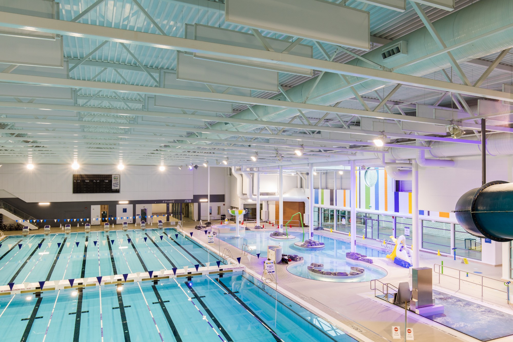 A photo of a large swimming pool with multiple lanes and bright purple lights.