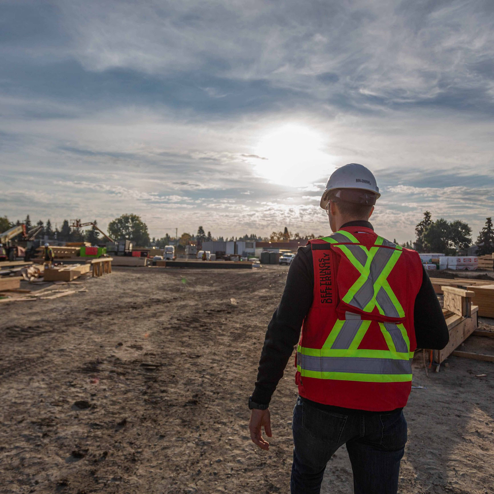 One Chandos construction worker walking on site at sunset, wearing a vest that reads 