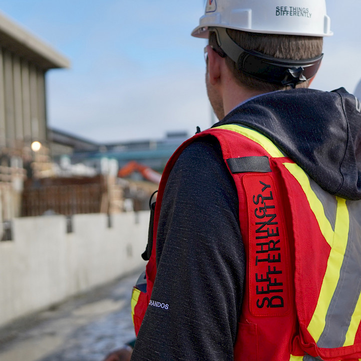 A Chandos construction worker looking onto their site wearing a safety vest that reads: 