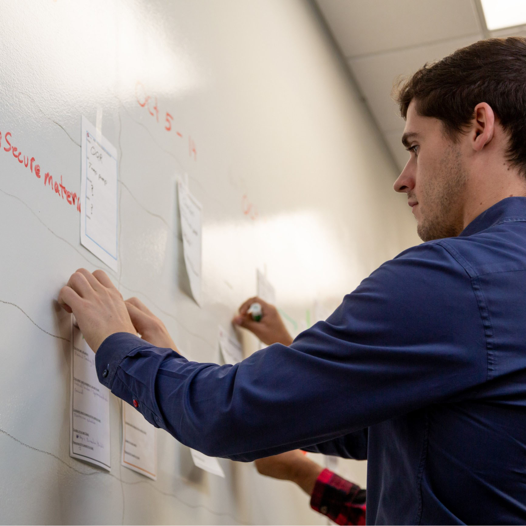 A Chandos office workers taping notes to a whiteboard during a meeting.