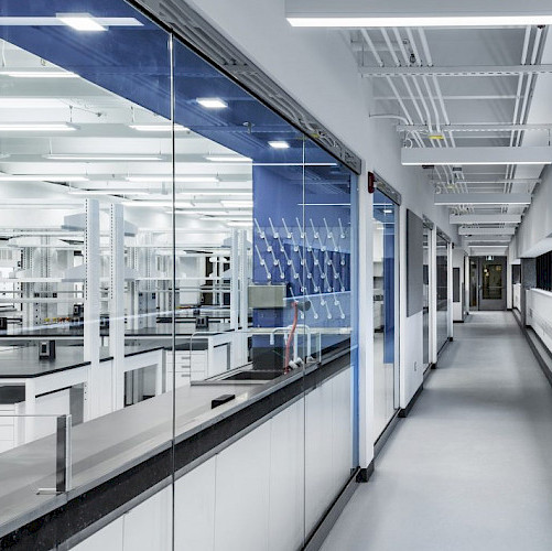 A sleek grey hallway in the Life Sciences Research laboratory at York University in Toronto, Ontario, with windows showcasing laboratory equipment.