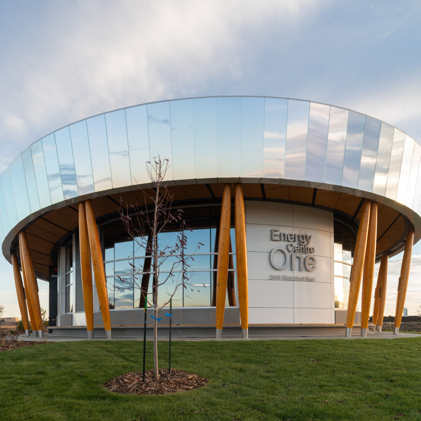 A photo of the Blatchford District Energy System, featuring it's mirrored exterior reflecting onto a cloudy blue sky.