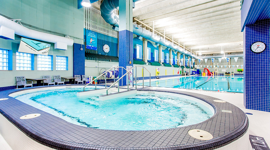 A hot tub in front of a large pool with multiple lanes.