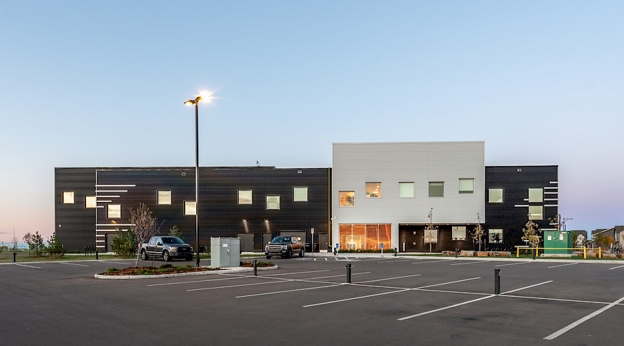 An empty parking lot in front of the black and white brick exterior of Garth Worthington school in the evening.