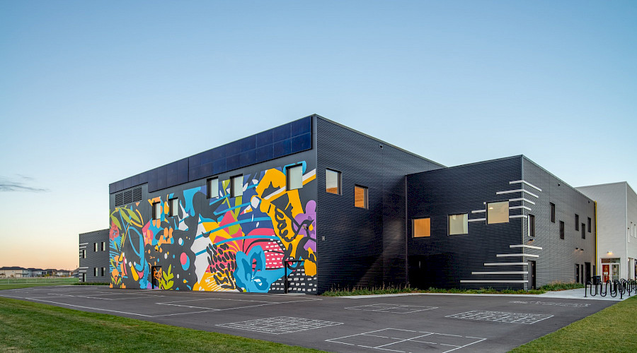 A colourful mural on the black brick exterior of Garth Worthington school.