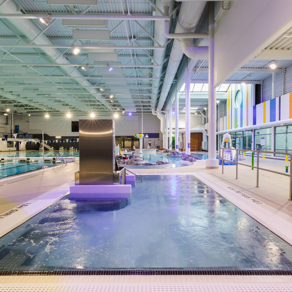 An overhead shot of a large swimming pool with purple lights lighting up the facility.