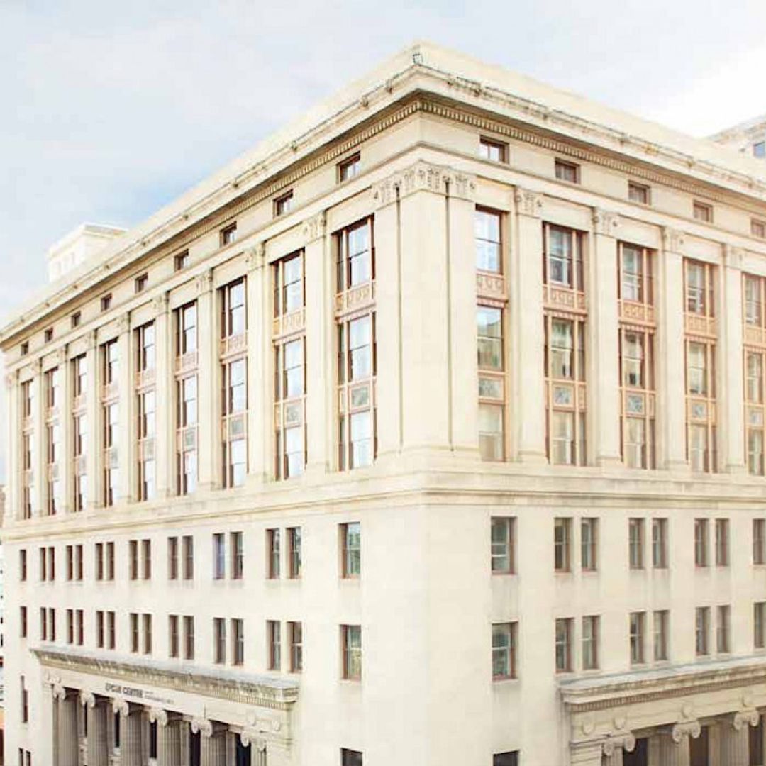 A photo of an older, cream coloured building with many windows and architectural details.