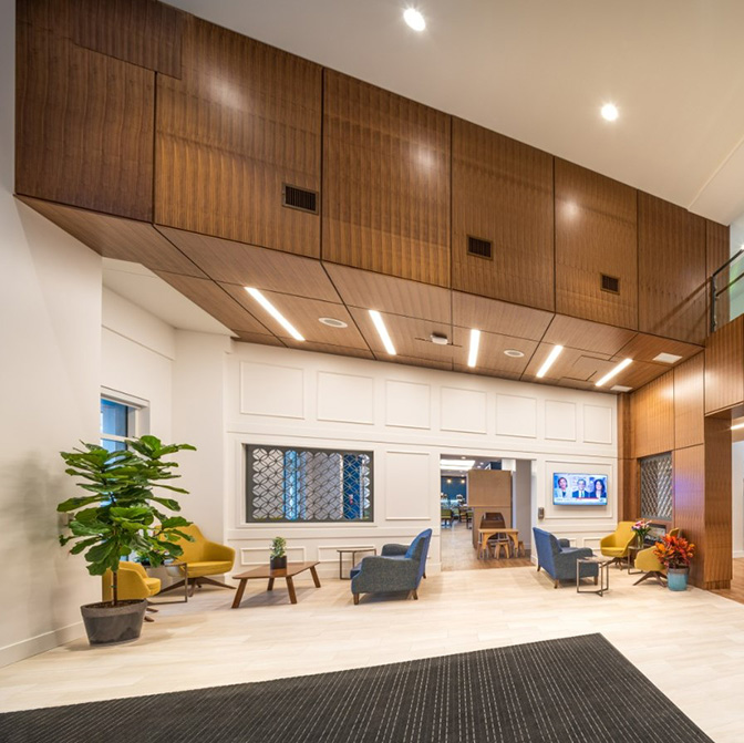 A seating area and coffee table with a plant in the lit up lobby of an urban building.