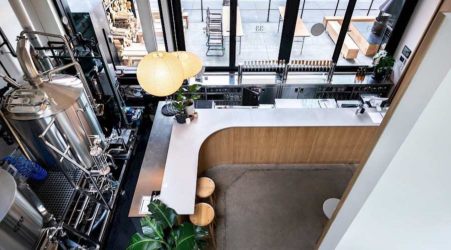 An aerial shot of a bar top in a brewery with brewing tanks on display. At the The Central Taps and 33 Acres restaurant and 33 Acres Brewing bar in downtown Calgary