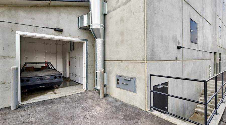 An old car parked in a open garage in the emergency services building.