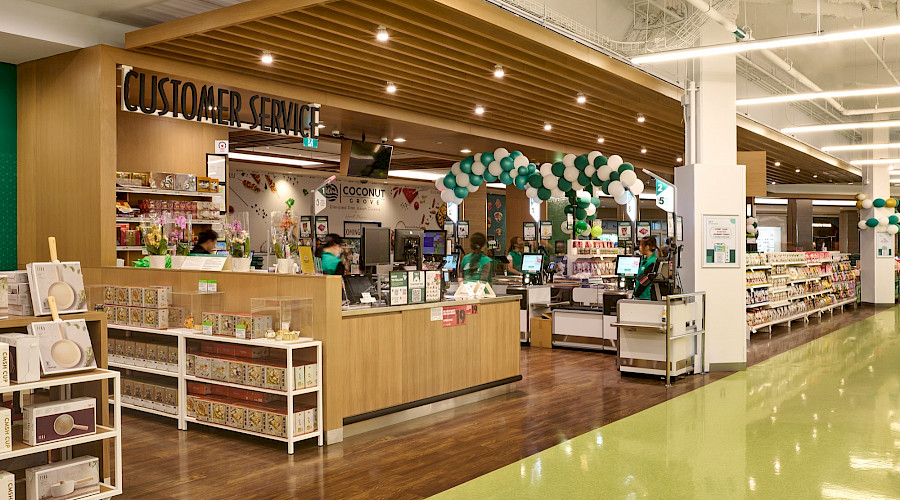 People working behind tils in the Customer Service area of a supermarket.