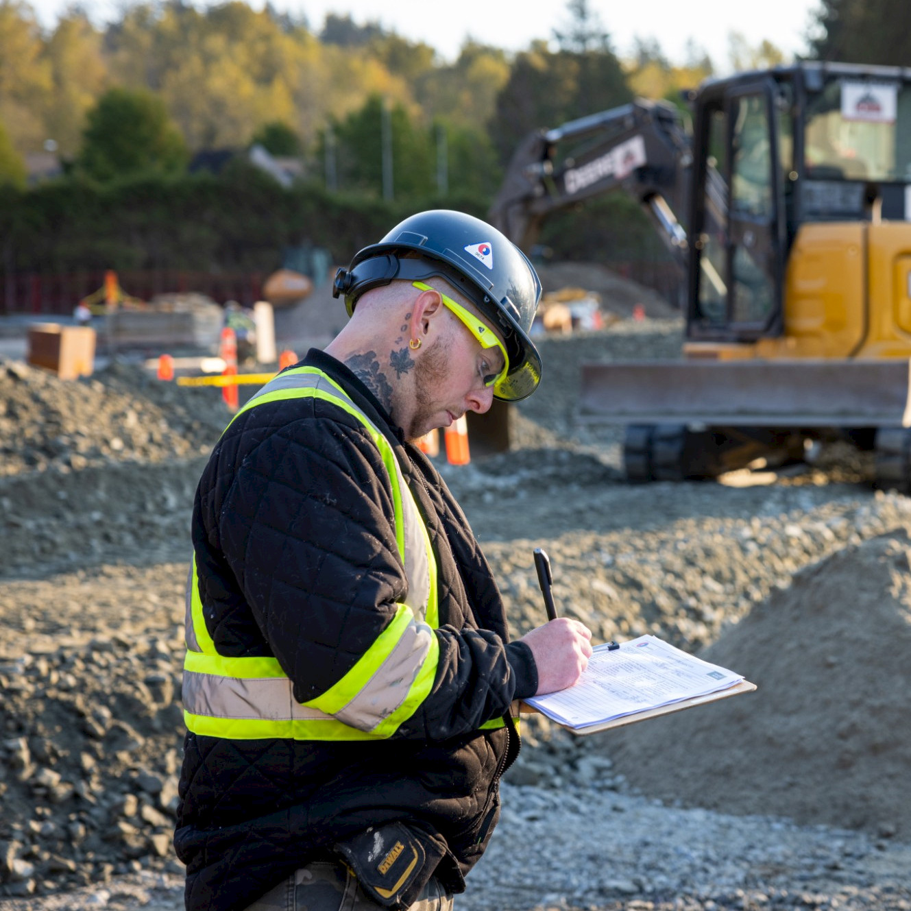 Two Chandos employees sit in an onsite office meeting space with a laptop in their safety gear.