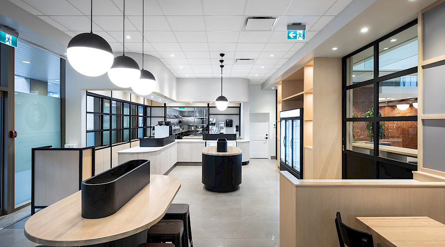 Image of the Seed n Salt dining room with light oak wall fixtures, window fixtures, and leather seating completed by Chandos Construction Calgary.