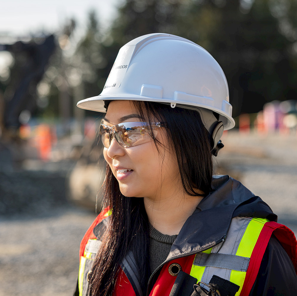 A female construction worker on site measuring wood pieces to cut