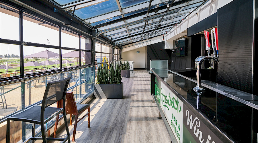 Interior shot of the secondary bar with glass garage doors that roll up during good weather at the Woodbine Apron Patio, built by Chandos Construction Toronto