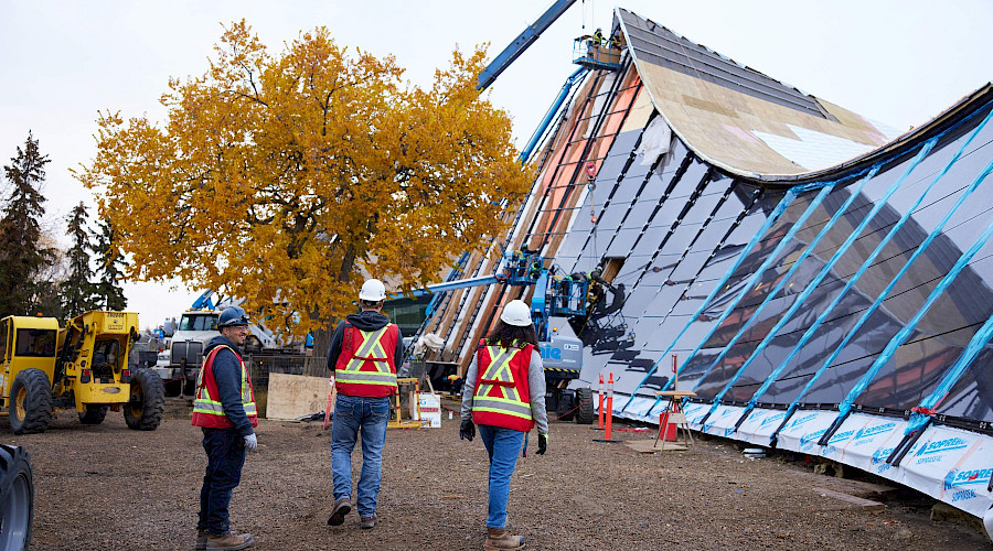 Image of three Chandos Construction workers in Edmonton completing a site visit at Peter Hemingway Leisure Centre during fall, highlighting the interesting architectural shape of the building.