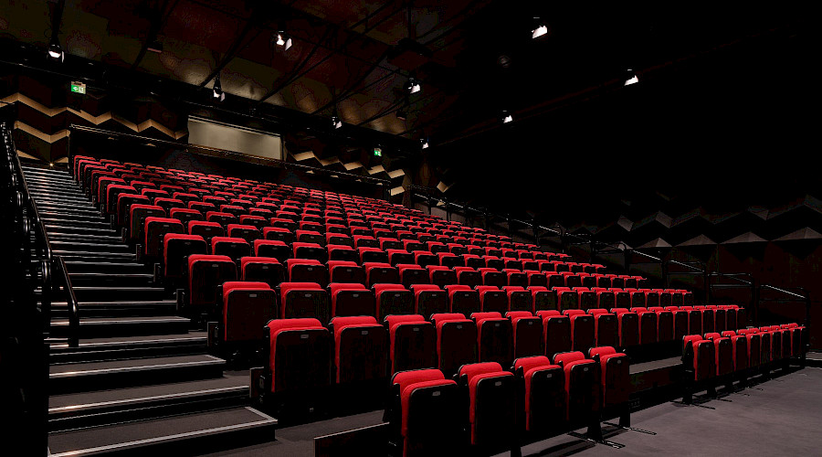 Interior image of the performing arts centre at he new Aurora Town Square centre built by Chandos Construction Toronto. The chairs feature plush red upholstery and black floors.